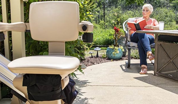 Paramount Living Aids Homepage Image featuring Woman Reading Outdoors by Outdoor Seatlift